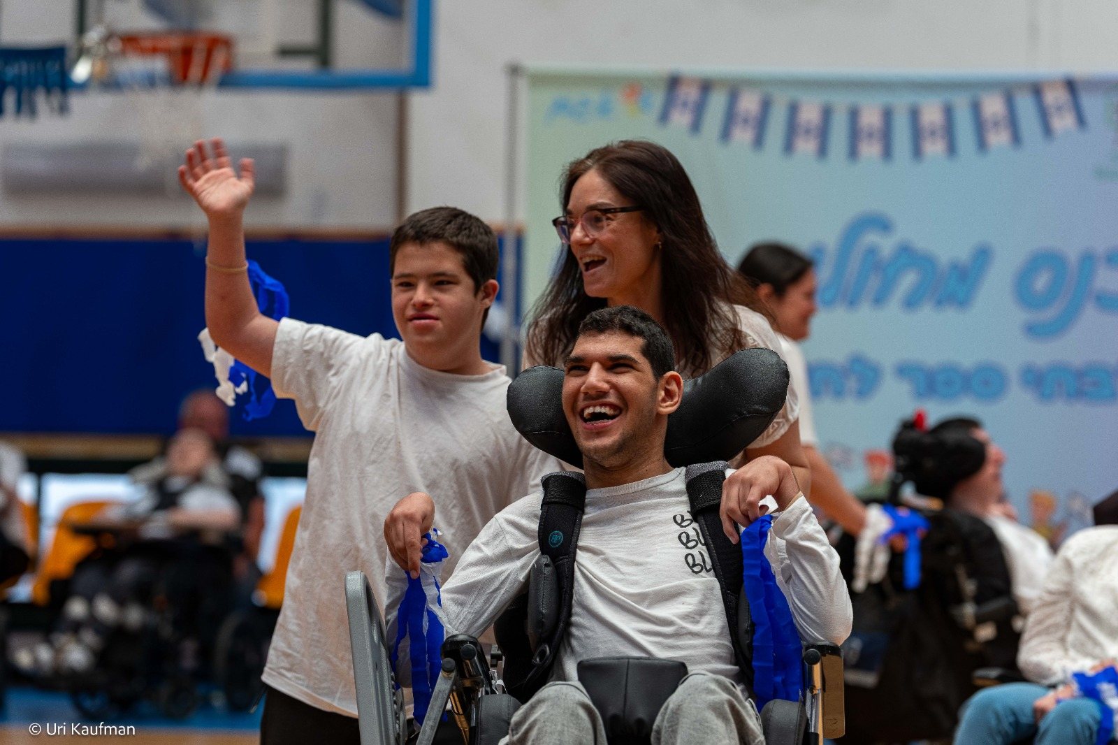 Two special-education students laughing joyfully at the conference, one waving and one in a wheelchair